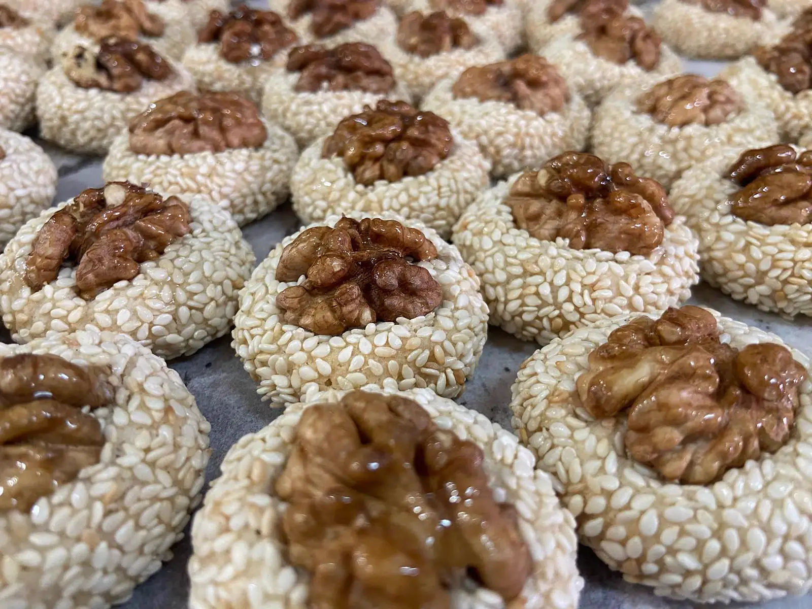 Biscuits enrobés de sésame garnis d'une noix, sur plaque de cuisson