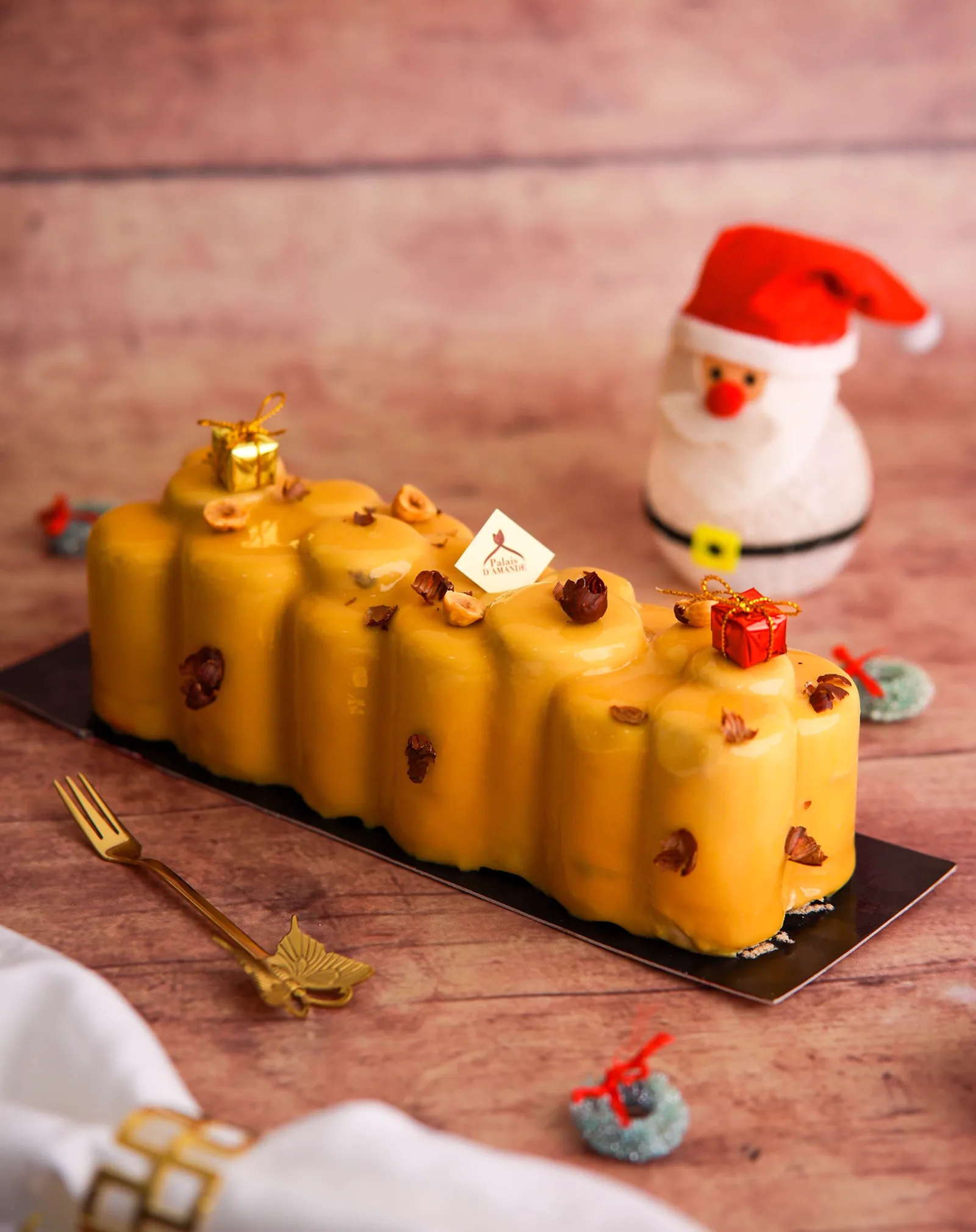 Bûche de Noël glaçage jaune mangue, noisettes, décor Père Noël