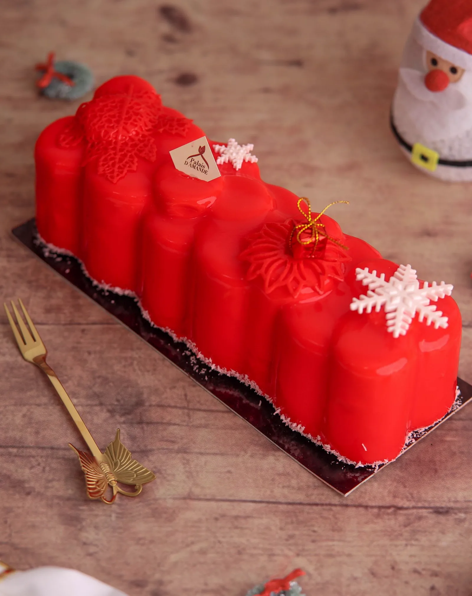 Bûche de Noël glaçage rouge avec flocons de neige et nœud doré